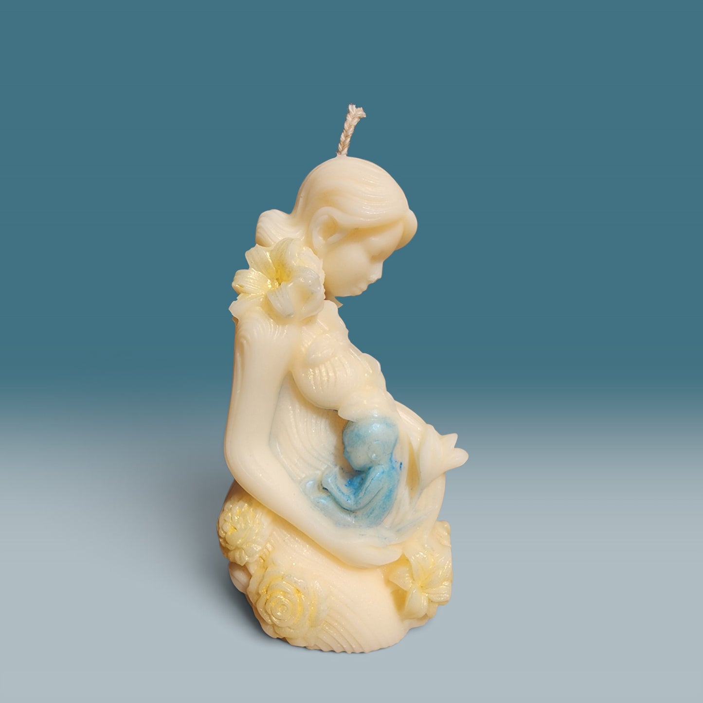 Enchanted Wicks Motherhood sculpted pillar candle in creamy wax with blue baby detail and floral accents.