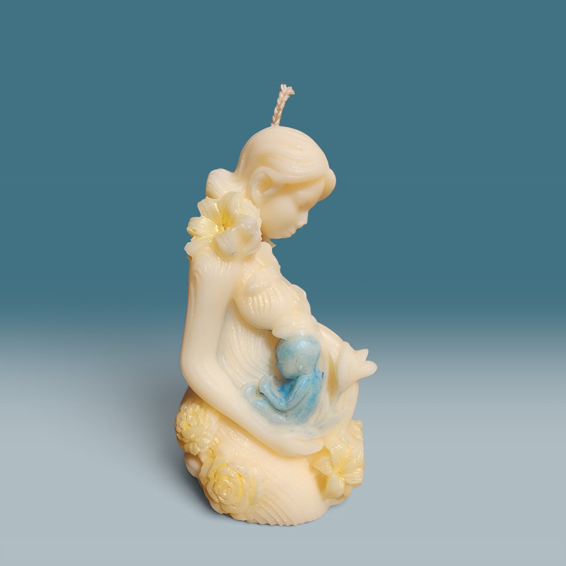 Enchanted Wicks Motherhood sculpted pillar candle in creamy wax with blue baby detail and floral accents.