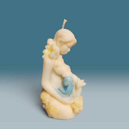 Enchanted Wicks Motherhood sculpted pillar candle in creamy wax with blue baby detail and floral accents.