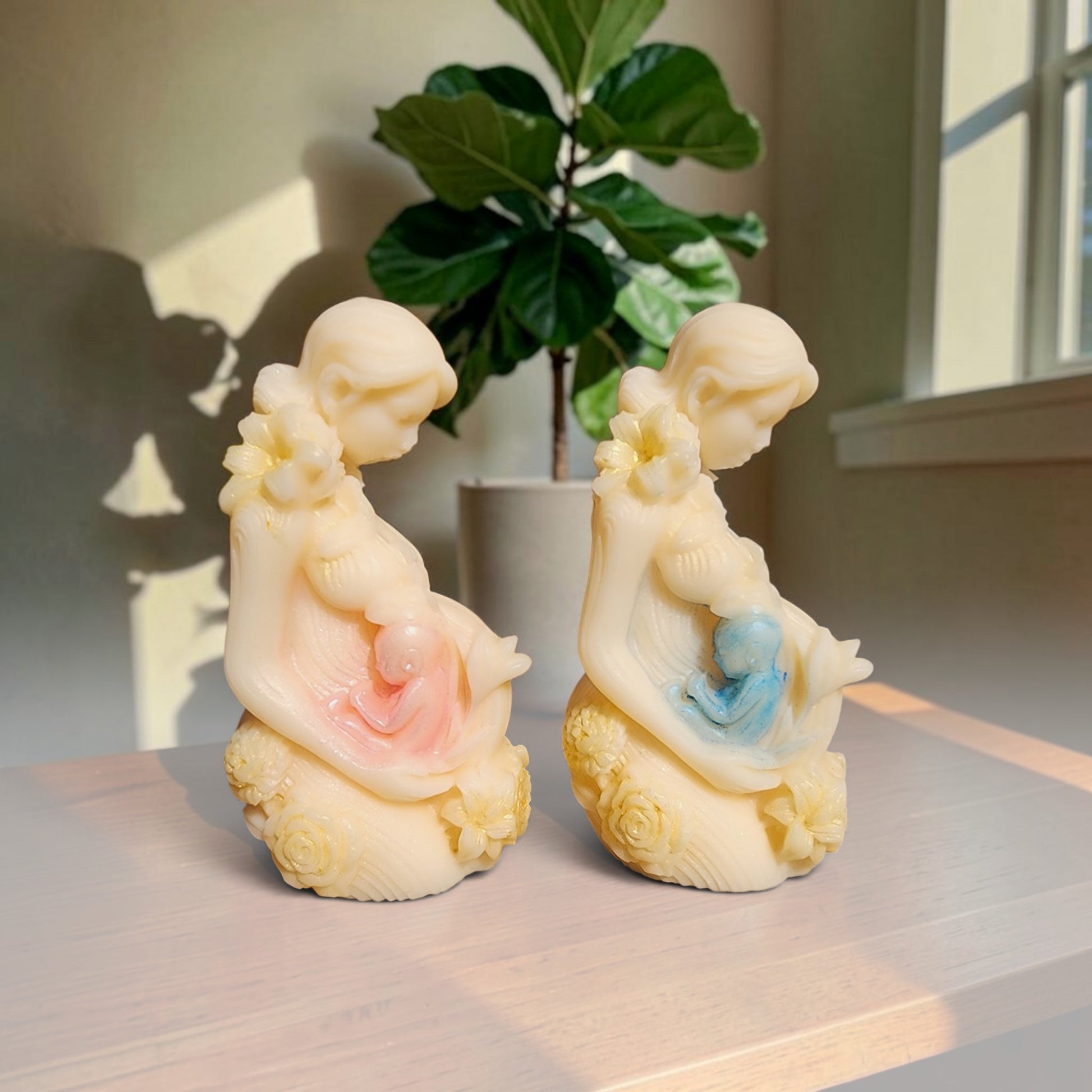 Enchanted Wicks sculpted pillar candles featuring mother and child silhouettes with pink and blue accents on a mantle.