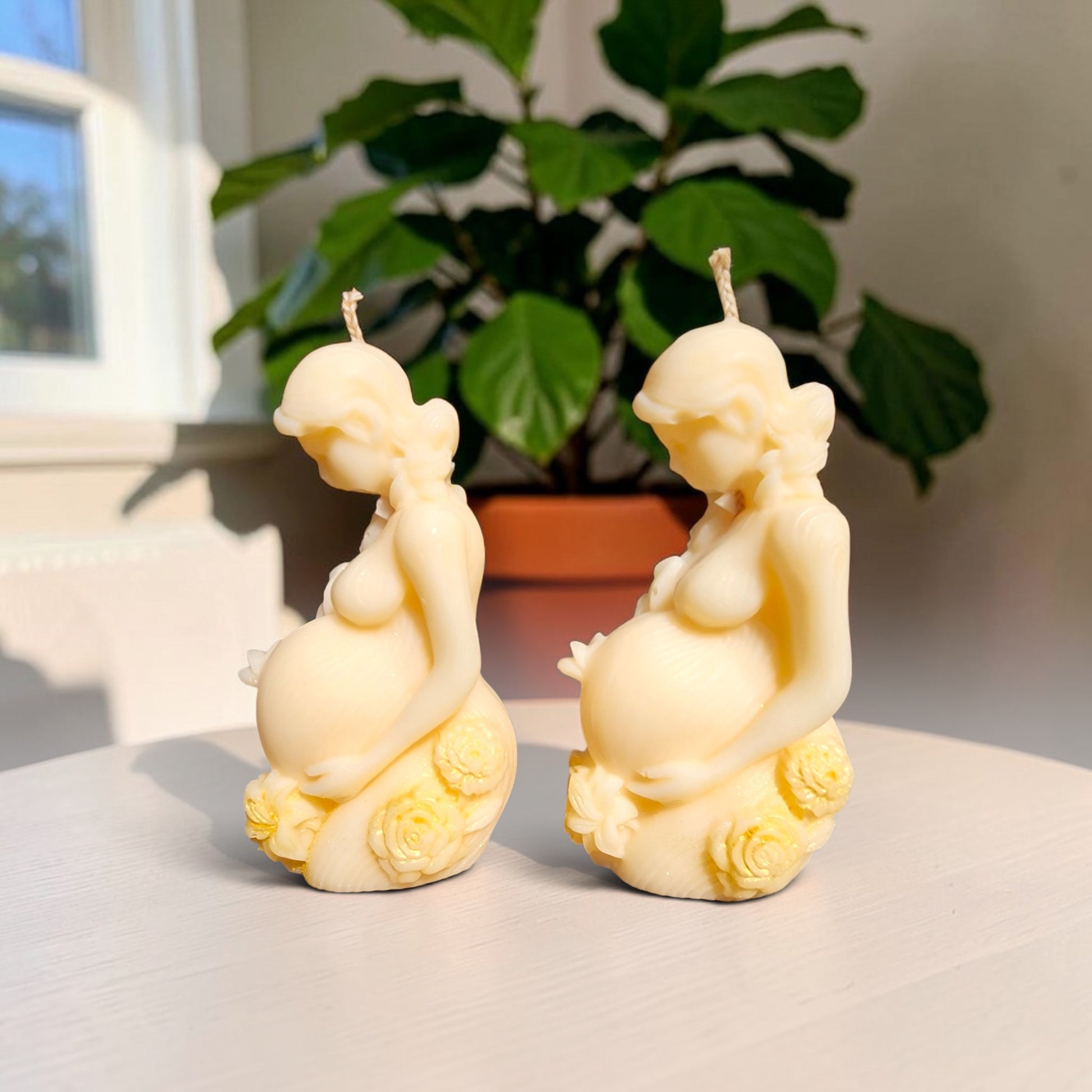 Enchanted Wicks sculpted pillar candles featuring a pregnant mother figure with floral accents in creamy wax tones.